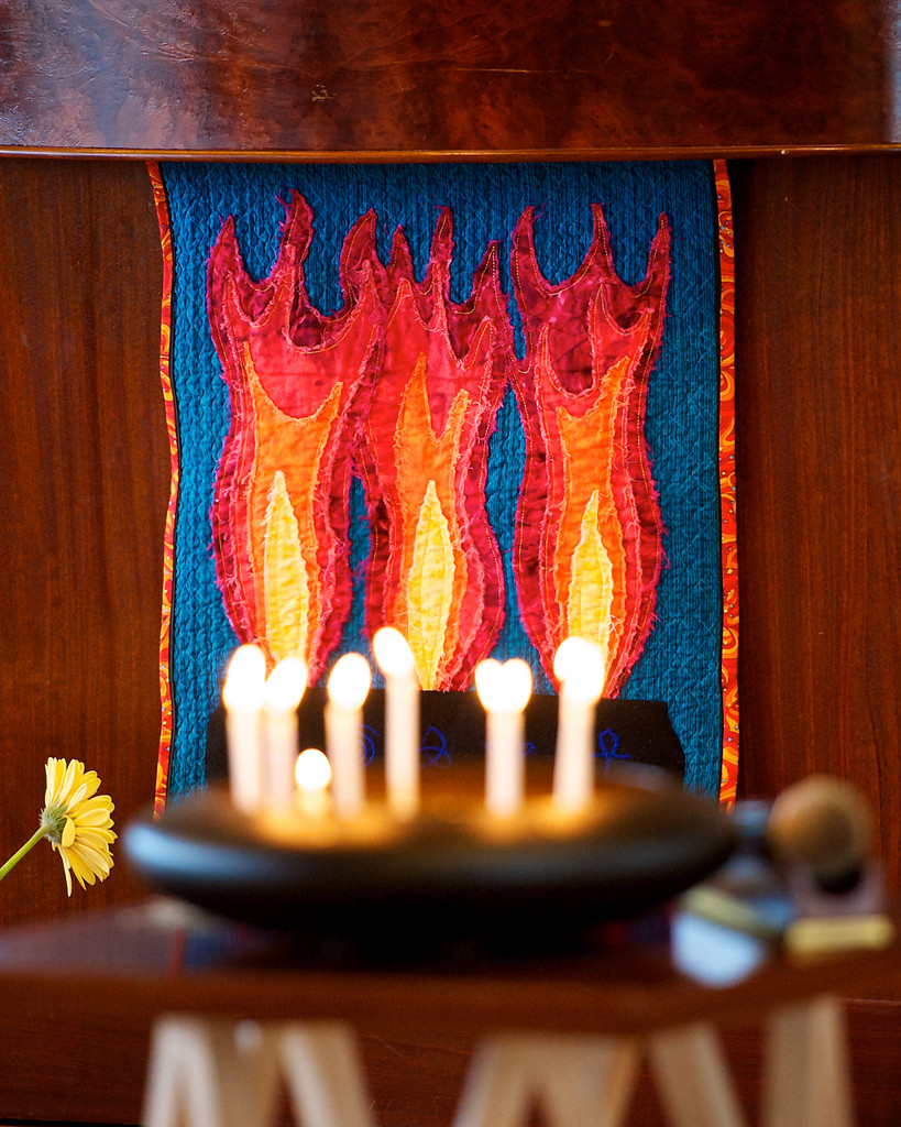 A tray of candles placed in front of a quilt displaying candles
